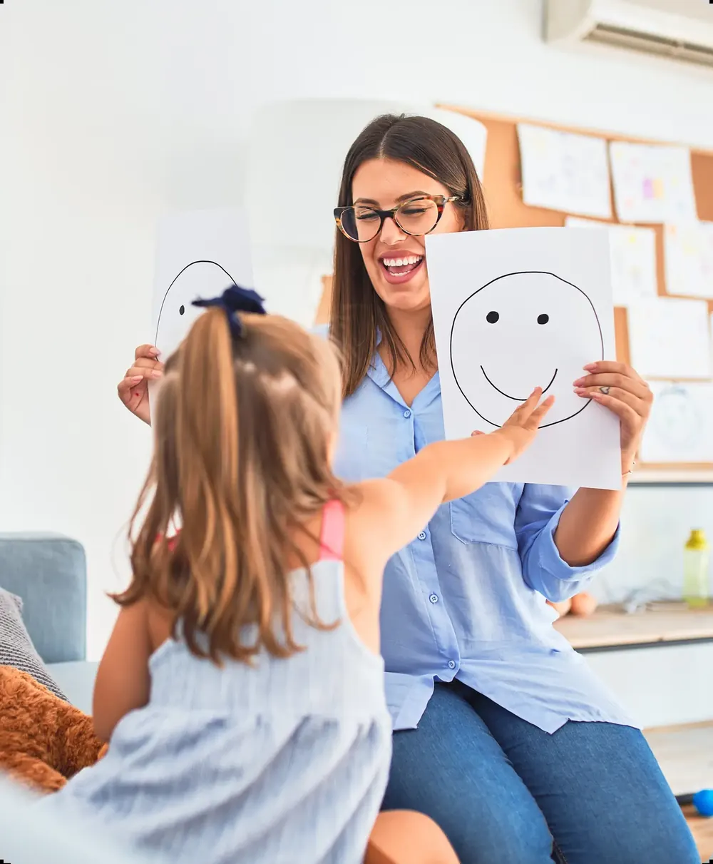 Una psicologa mostra a una bambina i disegni delle emozioni